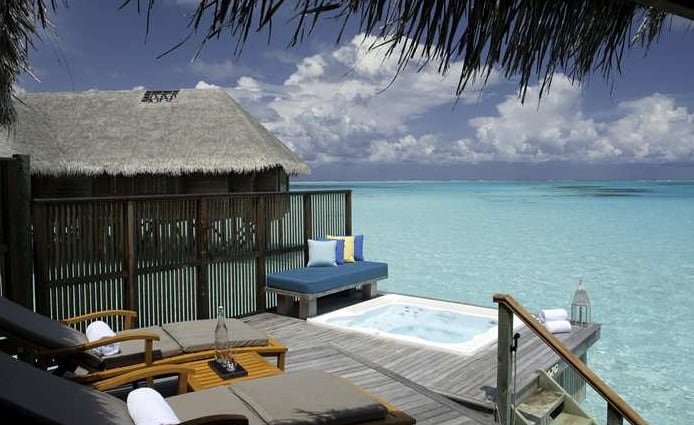 The deck of the family water villa has a whirlpool and steps into the ocean.